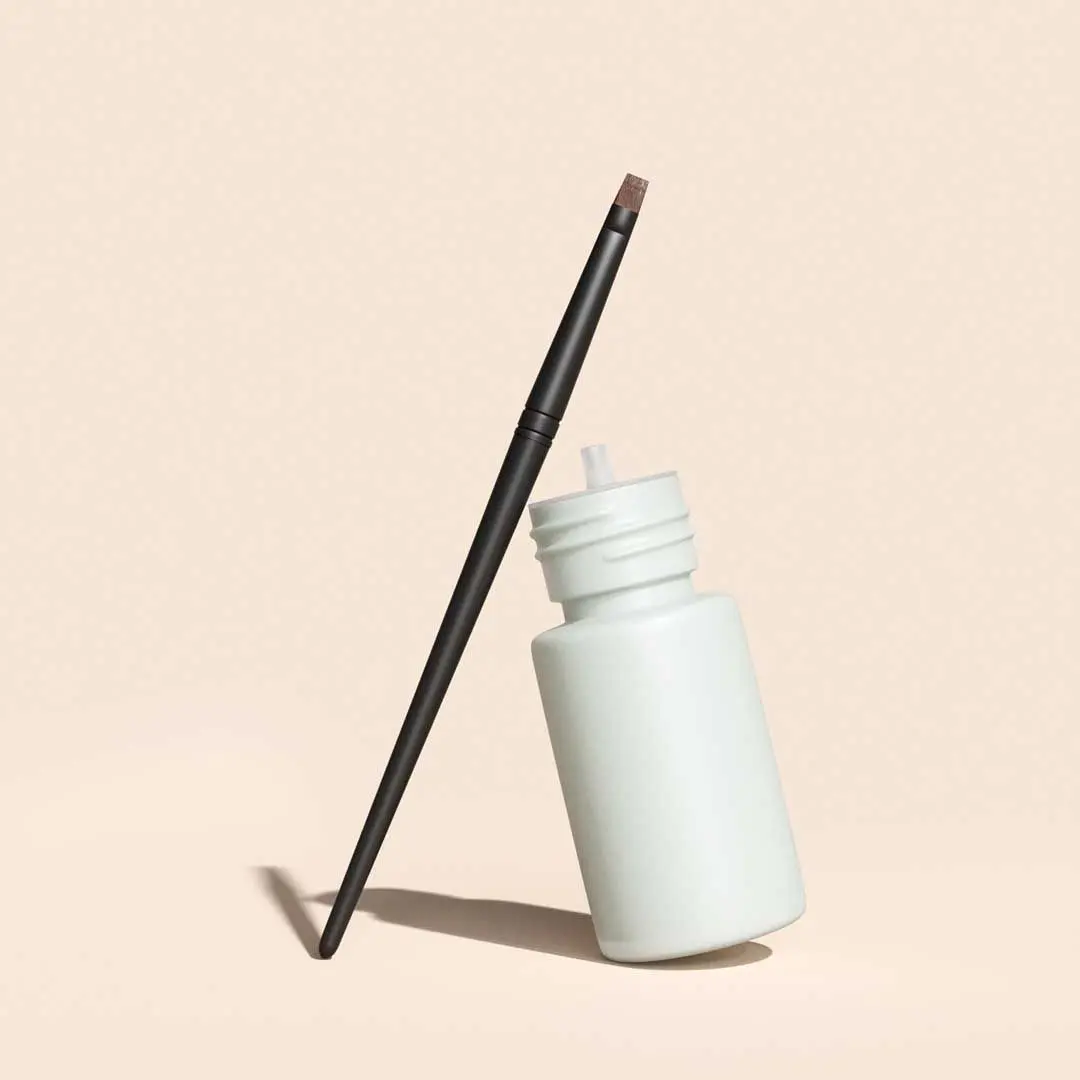 A bottle of Bimatoprost and applicator brush on a cream surface