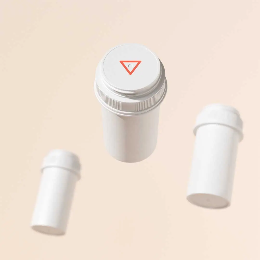3 floating Wisp pill vials with a cream background
