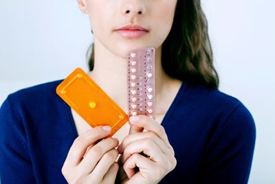 woman holds birth control and emergency contraception packets