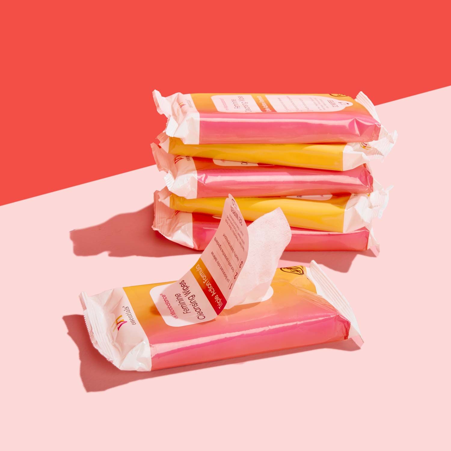 6 packages of pH Balancing Wipes on a pink surface with a red background
