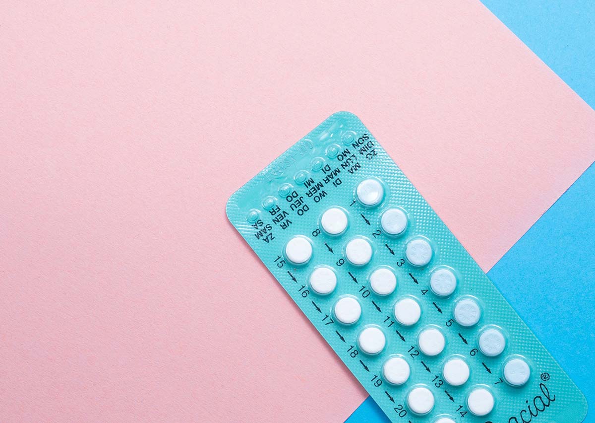 birth control pill packet on pink and blue background